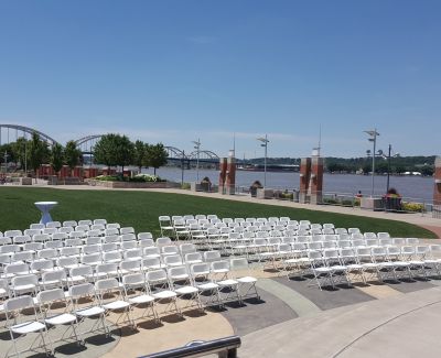A wedding ceremony outdoors with the river and bridge in the background.